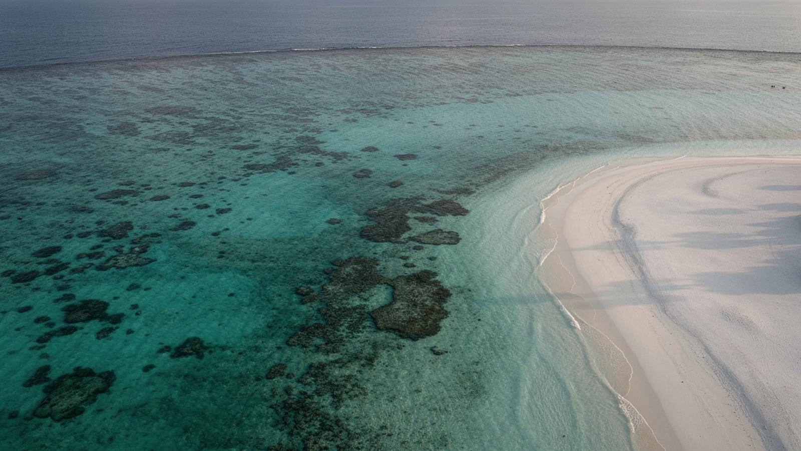 Turquoise reef lagoon and a white sandbank seen from above in the Maldives